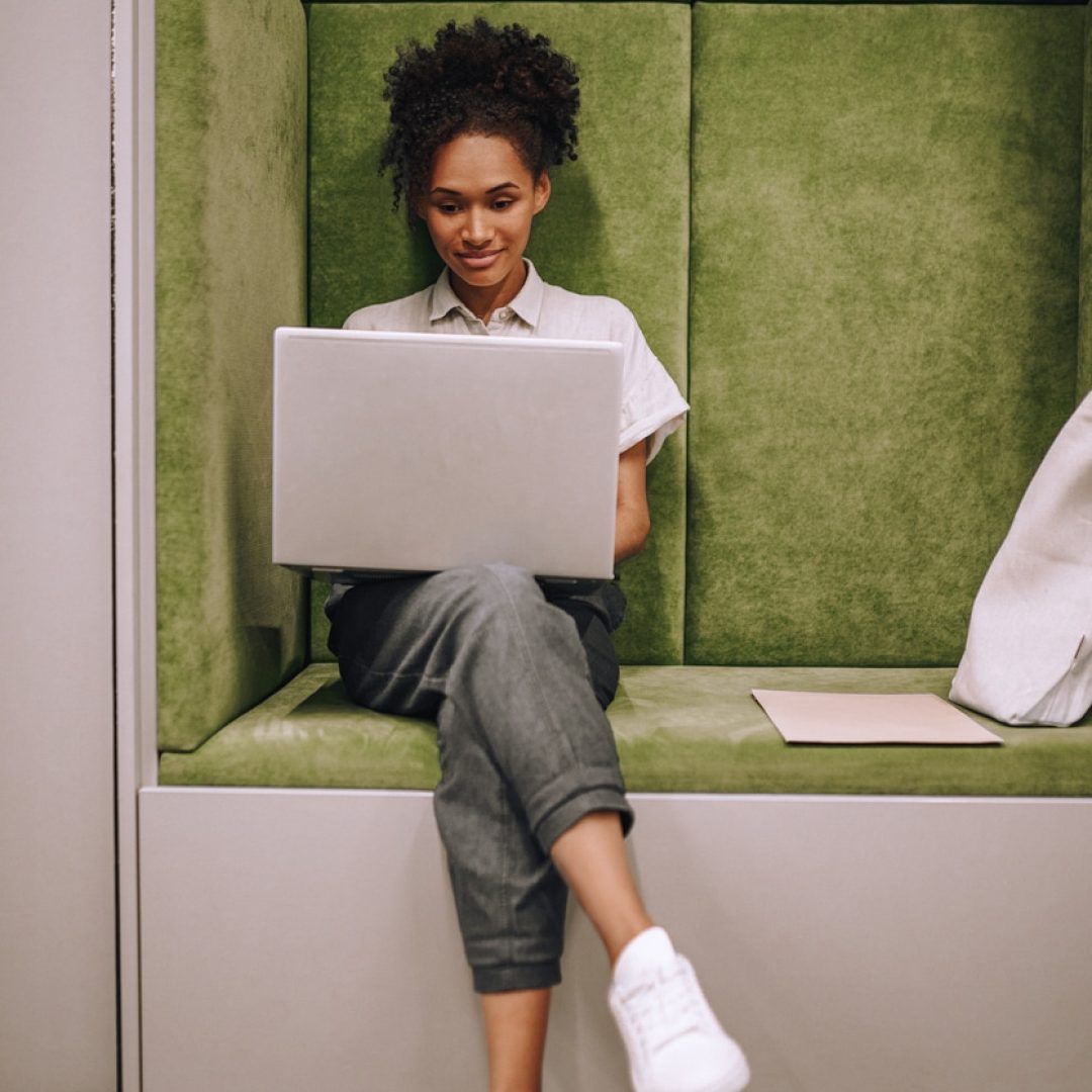 Employment. Young adult pretty woman in casual clothes working intently on laptop smiling sitting indoors